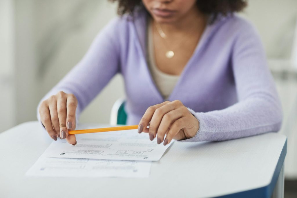 Un élève concentré en classe, tenant un crayon et une feuille d'examen.
